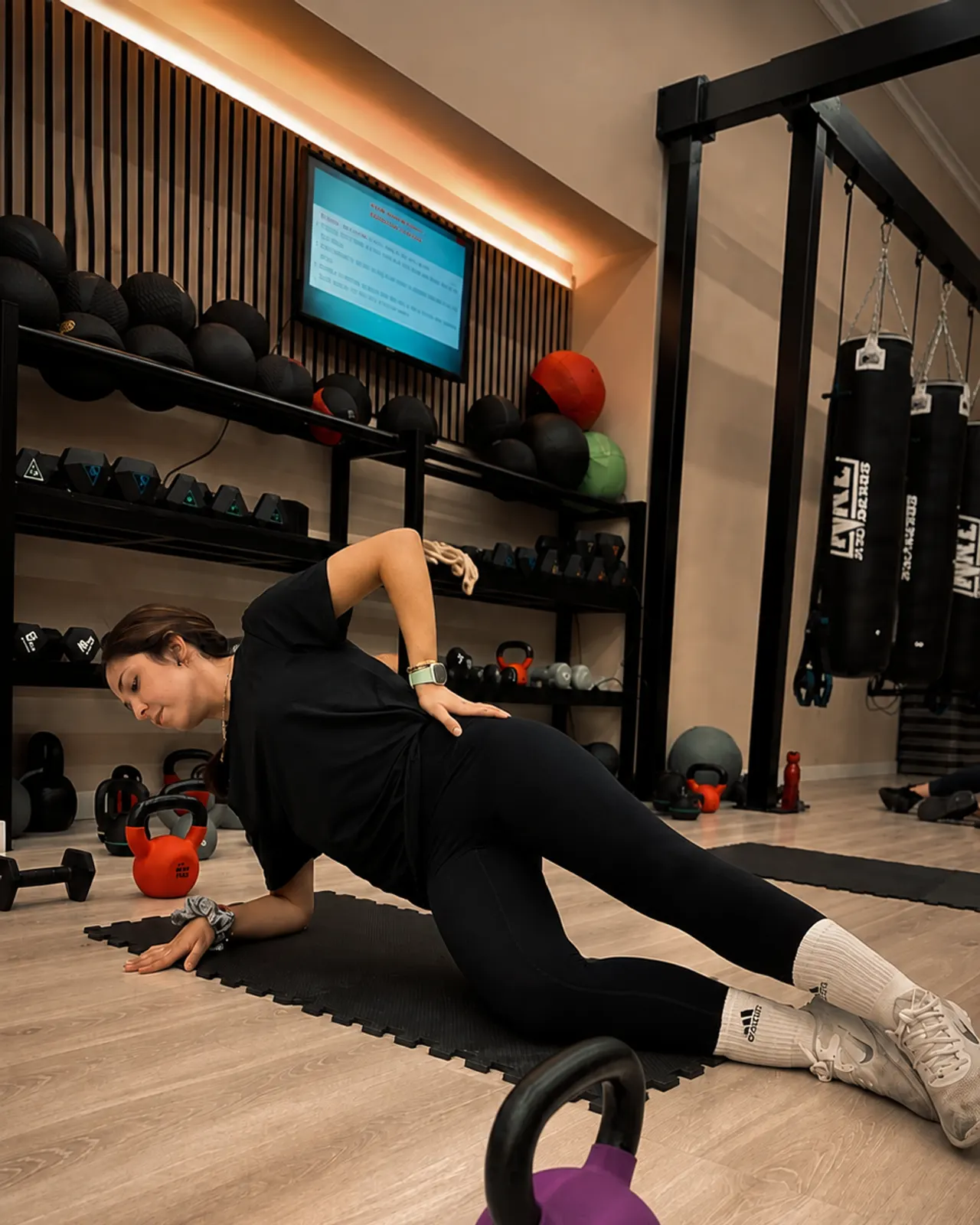 Plancha lateral con kettlebell, junto al mueble del material