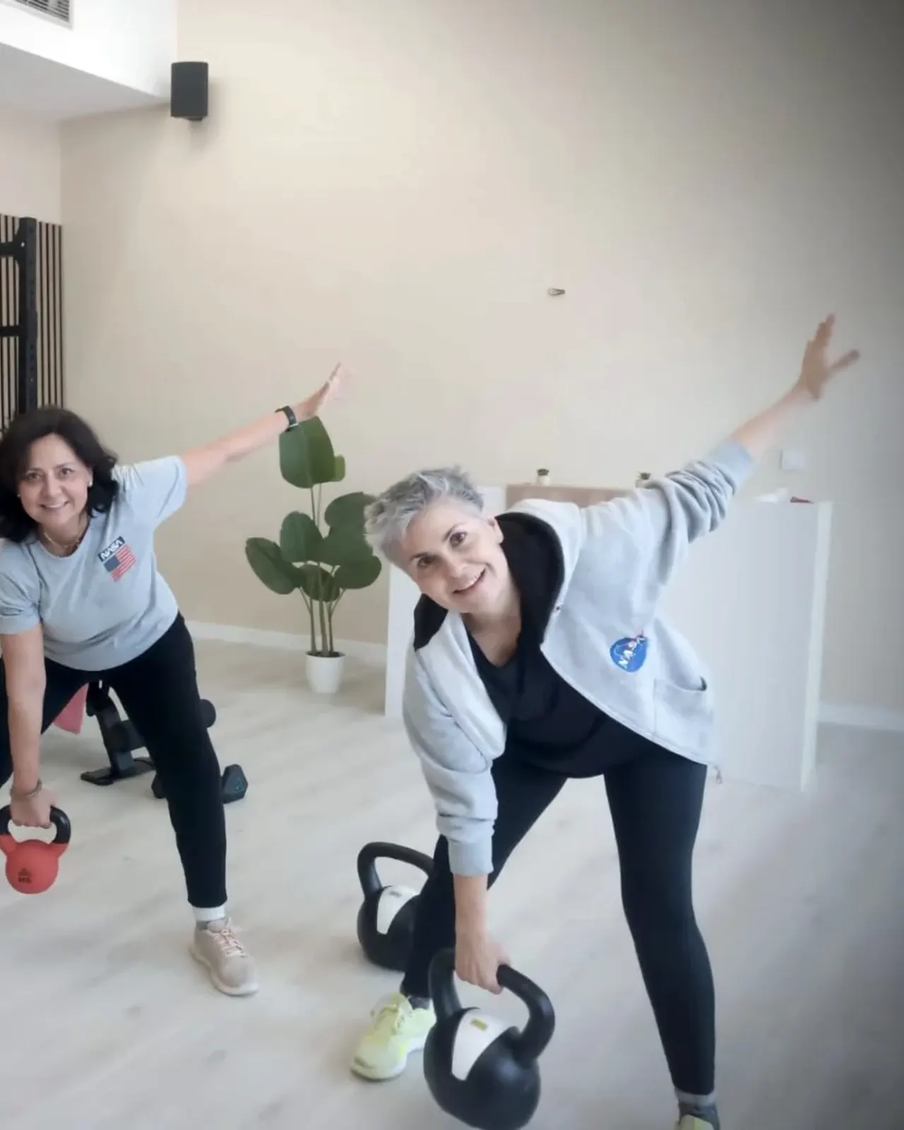 Dos personas entrenando con kettlebells junto a la jaula de fuerza